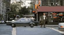 a man crosses a street in front of a store that says pizza