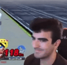 a man is sitting in front of a computer screen playing a video game and smiling .
