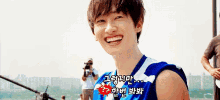 a young man wearing a blue and white shirt is smiling while standing in front of a body of water .