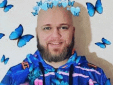 a bald man with a beard and a crown of butterflies on his head is smiling .