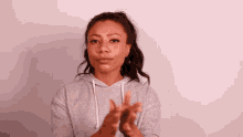 a woman in a grey hoodie is clapping her hands together