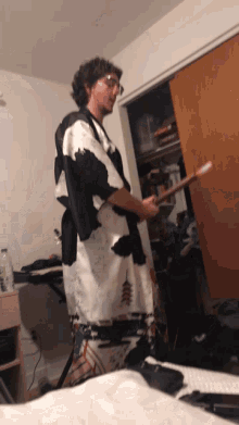 a man in a black and white kimono is holding a drumstick