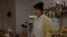 a woman in a kitchen says welcome in front of a sign that says netflix