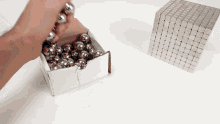a box of metal balls next to a cube