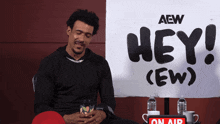 a man is sitting in front of a sign that says hey