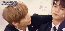 a man in a suit is kissing another man on the cheek with flowers in his hair .