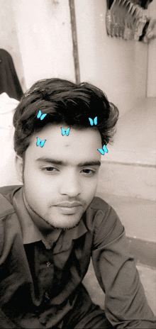 a black and white photo of a young man with butterflies on his forehead