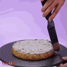 a person is spreading frosting on a cake on a plate that says yum up !