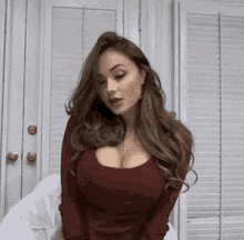the woman is wearing a red shirt with a plunging neckline and large breasts .