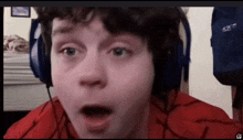 a young boy wearing headphones and a red shirt looks surprised .