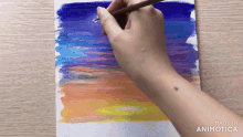 a person is painting a sunset with colored pencils and the words made in animotica are visible