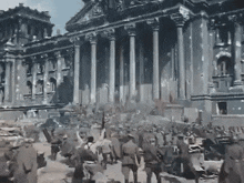 a group of people are walking in front of a building with columns