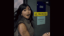 a woman is standing in front of a sign that says " mind the stag "