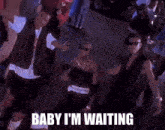 a group of men are dancing in a crowd with the words baby i 'm waiting above them