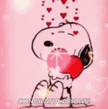 snoopy is holding a red heart in his hands on a pink background with hearts coming out of his mouth .