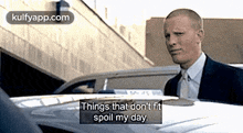 a man in a suit and tie is standing in front of a police car and saying things that don 't fit spoil my day .