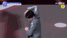 a man in a suit is dancing on a stage with a mnet logo in the background .
