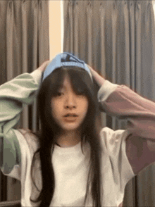 a girl wearing a blue hat and a white shirt holds her head