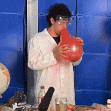 a man blowing up a red balloon in front of a globe
