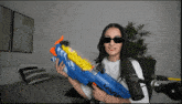 a woman wearing sunglasses is holding a toy gun that says levie