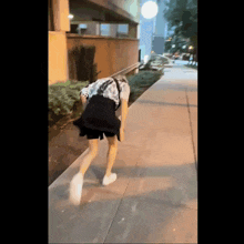 a person walking down a sidewalk with their head on their knees