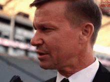 a man in a suit and tie is talking into a microphone with a red bull logo behind him