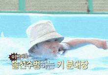 a person wearing a bucket hat is swimming in a pool with korean writing on the bottom