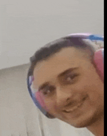 a man wearing pink and blue headphones is smiling for the camera .