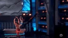a man is flying through the air on a stage with the words #titangames on the bottom
