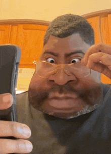 a man wearing glasses and a black shirt looks at his phone