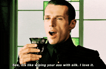 a man is holding a wine glass and saying see it 's like wiping your ass with silk