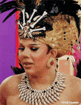 a woman wearing a feathered headdress and a necklace with seashells and bones