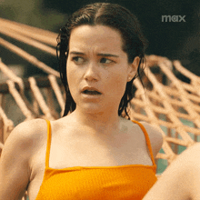 a woman in an orange tank top is standing in front of a hammock with the word max on the bottom