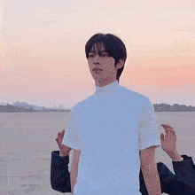 a young man wearing a white shirt stands in a field