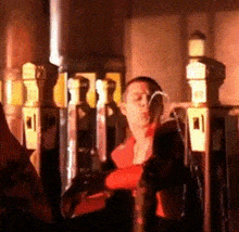 a man in a red shirt is sitting in front of a row of telephones .