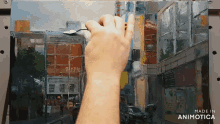 a person is painting a city street scene with a spoon in their hand