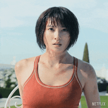a woman in a red tank top is standing in front of a netflix sign