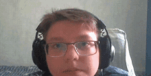 a young boy wearing headphones and glasses is sitting in a chair .