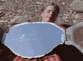 a boy is laying on the ground holding a large piece of metal