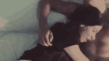 a man and a woman are laying on a bed . the woman is laying on the man 's lap .