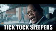 a man in a suit is sitting in a car with the words `` tick tock sleepers '' written on it .