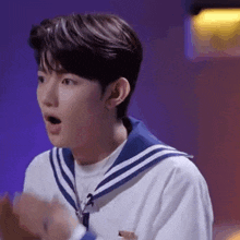 a young man wearing a sailor suit and a white shirt is making a surprised face .