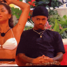 a woman in a bikini sits next to a man in a black shirt