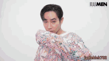 a man covering his face with a colorful sweater with elle men thailand written on the bottom