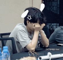 a man with bunny ears on his head is covering his face with his hands