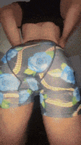 a woman wearing a black bra and blue shorts with a floral pattern