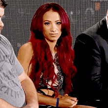 a woman with long red hair is sitting in front of a crowd .
