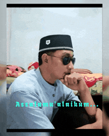 a man wearing sunglasses and a hat with the word assalamu ' alaikum written on it