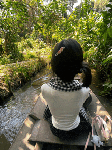 a girl in a white shirt is sitting in a boat looking out over a river