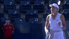 a woman wearing a white visor is standing in front of empty seats